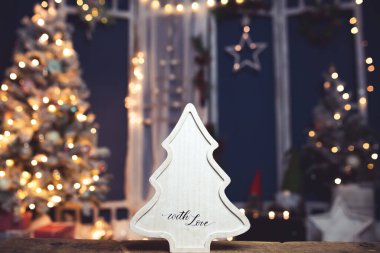 Kış, tatiller ve dekorasyon konsepti. Parlak tatil ışıkları üzerine ahşap Noel ağacı.