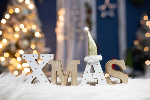 在明亮的节日灯火和圣诞树前的字母Xmas — 图库照片
