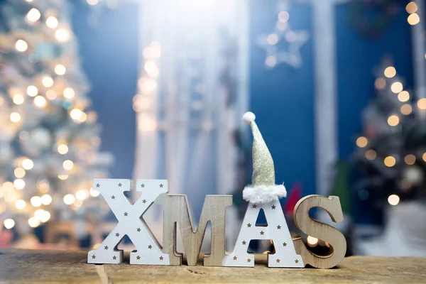 在明亮的节日灯火和圣诞树前的字母Xmas — 图库照片
