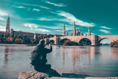 Man doing sightseeing in Zaragoza.Tourist sitting at Ebro river bank and enjoying Basilica del Pilar view.