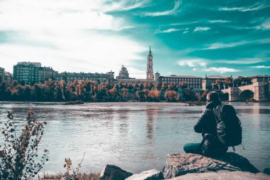 Man doing sightseeing in Zaragoza.Tourist sitting at Ebro river bank and enjoying Basilica del Pilar view.
