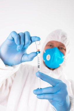 COVID-19 koronavirüs aşısı. Aşı konsepti. Doktorun elinde mavi eldivenler ilaç aşısı şişesi ve şırınga var.. 