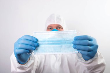 Doktor eli mavi tıbbi eldiven takıyor. Pandemik hastalıklar için antivirüs maskesi taşıyor. Salgın, Covid19 konsepti