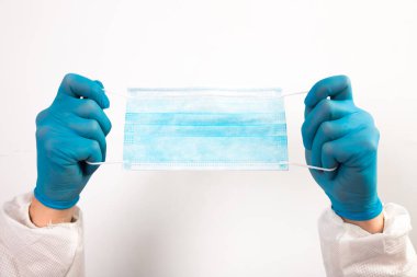 Doktor eli mavi tıbbi eldiven takıyor. Pandemik hastalıklar için antivirüs maskesi taşıyor. Salgın, Covid19 konsepti