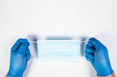 Doktor eli mavi tıbbi eldiven takıyor. Pandemik hastalıklar için antivirüs maskesi taşıyor. Salgın, Covid19 konsepti