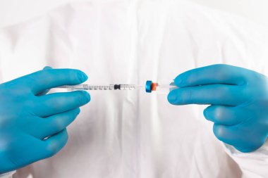 COVID-19 koronavirüs aşısı. Aşı konsepti. Doktorun elinde mavi eldivenler ilaç aşısı şişesi ve şırınga var.. 