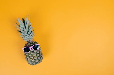 Renkli arka planda güneş gözlüklü ananas. Yaz tatili ya da tatil kavramı.