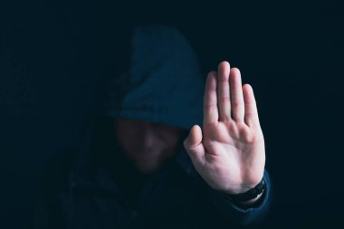 Siyah arkaplanda dur işareti gösteren bir adam