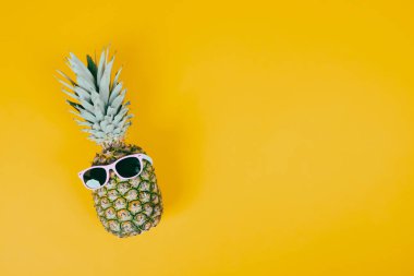 Renkli arka planda güneş gözlüklü ananas. Yaz tatili ya da tatil kavramı.