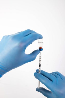 COVID-19 koronavirüs aşısı. Aşı konsepti. Doktorun elinde mavi eldivenler ilaç aşısı şişesi ve şırınga var..