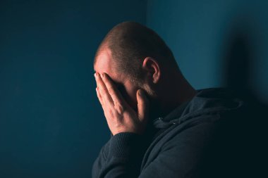Karanlık odada oturan üzgün adam. Depresyon ve endişe kavramı