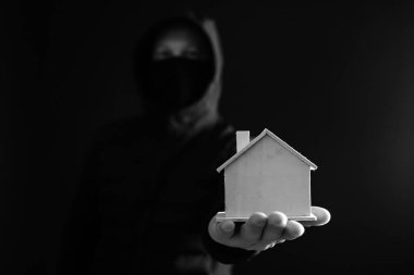 Haneye tecavüz konsepti. Gizlenmiş davetsiz misafir elinde küçük bir ev tutuyor. Gece karanlığında maskeli bir hırsız. 