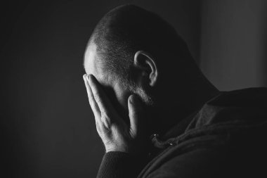 Karanlık odada oturan üzgün adam. Depresyon ve endişe kavramı