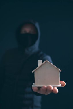 Haneye tecavüz konsepti. Gizlenmiş davetsiz misafir elinde küçük bir ev tutuyor. Gece karanlığında maskeli bir hırsız. 