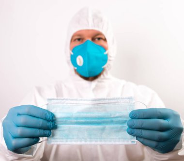 Doktor eli mavi tıbbi eldiven takıyor. Pandemik hastalıklar için antivirüs maskesi taşıyor. Salgın, Covid19 konsepti