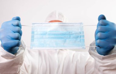 Doktor eli mavi tıbbi eldiven takıyor. Pandemik hastalıklar için antivirüs maskesi taşıyor. Salgın, Covid19 konsepti