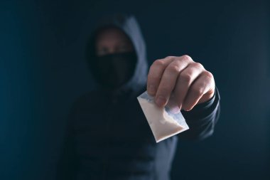 Bir doz kokain ya da eroin tutan bir bağımlı. Uyuşturucu satıcısı, uyuşturucu ticareti, suç, bağımlılık ve satış kavramı.