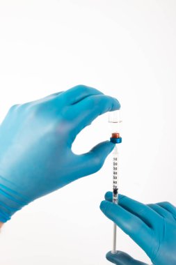 COVID-19 koronavirüs aşısı. Aşı konsepti. Doktorun elinde mavi eldivenler ilaç aşısı şişesi ve şırınga var..