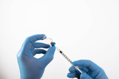 COVID-19 koronavirüs aşısı. Aşı konsepti. Doktorun elinde mavi eldivenler ilaç aşısı şişesi ve şırınga var..