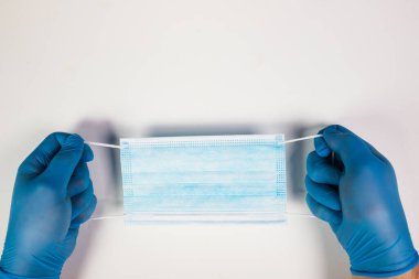 Doktor eli mavi tıbbi eldiven takıyor. Pandemik hastalıklar için antivirüs maskesi taşıyor. Salgın, Covid19 konsepti