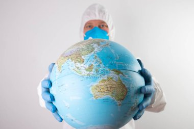 Dünya salgını tehlike kavramı. Dünya gezegenini koruyan tıbbi maskeli ve eldivenli erkek doktor..
