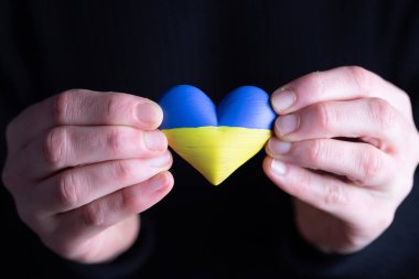 Ukrayna 'nın kalp şeklinde bayrağı kadınların elinde. Ukrayna vatandaşlarıyla dayanışma kavramı.