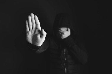 Üzgün, kızgın bir adam karanlık arka planda dur işareti gösteriyor. Düşük tuşlu fotoğraf.