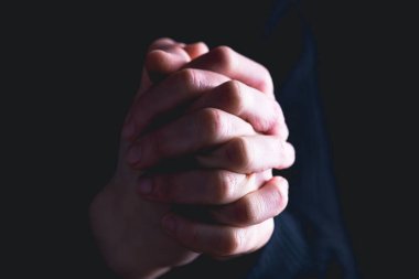 Karanlık arka planda din ve Tanrı'ya inanç ile dua eller. Umudun, sevginin ve bağlılığın gücü.