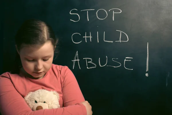 stock image Child violence and abused concept. Little sad girl with Stop child abuse text writted on a blackboard