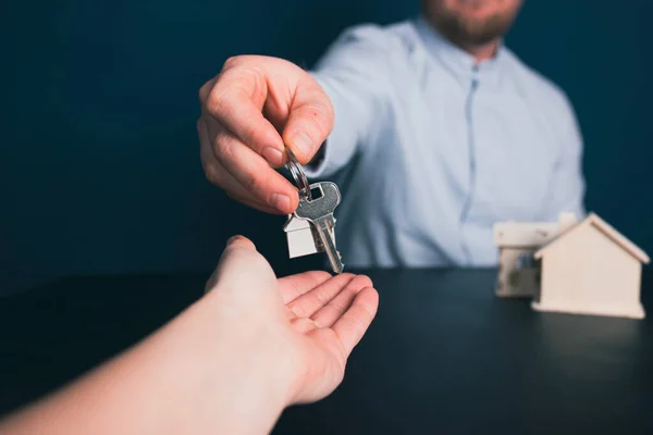 Businessman hands over house keys to client. The concept of a realtor, mortgage, your house, home loan.