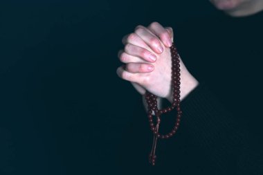 Dindar genç bir kadın Tanrı 'ya dua ediyor, karanlık arka planda..