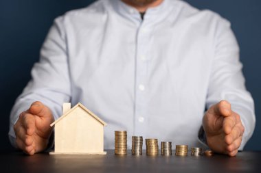 Ev modeli ve yığınla parası olan bir iş adamı. Emlakçı, ipotek, tasarruf parası, ev kredisi kavramı.. 