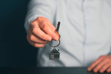 Emlakçının elinde anahtar var. Emlakçı, ipotek, evin, ev kredisi konsepti.
