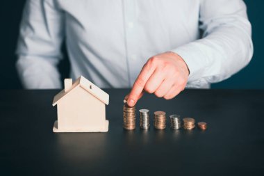 Ev modeli ve yığınla parası olan bir iş adamı. Emlakçı, ipotek, tasarruf parası, ev kredisi kavramı.. 