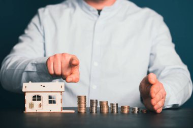 Ev modeli ve yığınla parası olan bir iş adamı. Emlakçı, ipotek, tasarruf parası, ev kredisi kavramı.. 