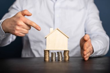 Ev modeli ve yığınla parası olan bir iş adamı. Emlakçı, ipotek, tasarruf parası, ev kredisi kavramı.. 
