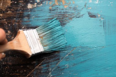 Kadının elindeki boya fırçası eski ahşabı mavi boyayla boyuyor. Yaratıcı tasarım, ev yenileme teması, DIY konsepti