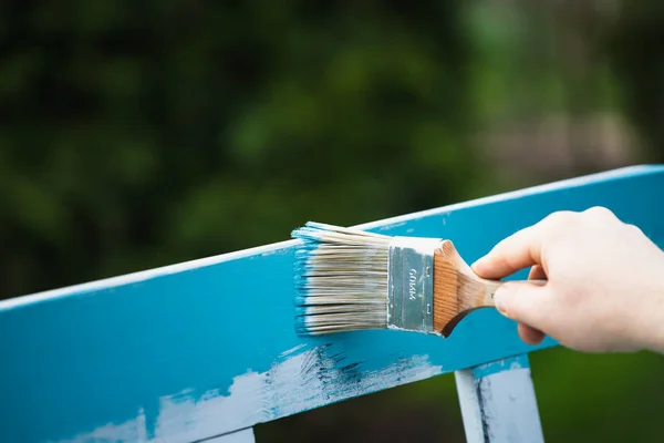Man painting wood furniture with turquoise chalk painting