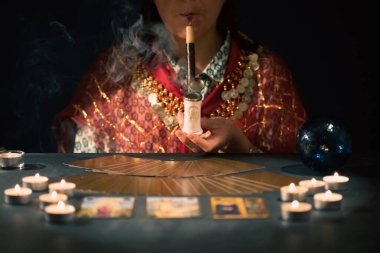 Falcı elinde mumların yanındaki masada tarot kartlarıyla. Tarot kartları kristal kürenin üzerine yayılmış. Tahmin konsepti..