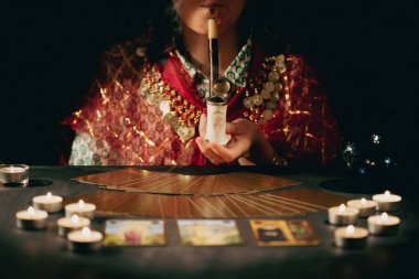 Falcı elinde mumların yanındaki masada tarot kartlarıyla. Tarot kartları kristal kürenin üzerine yayılmış. Tahmin konsepti..