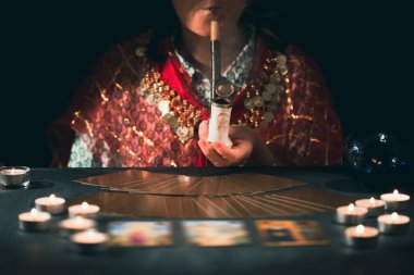 Falcı elinde mumların yanındaki masada tarot kartlarıyla. Tarot kartları kristal kürenin üzerine yayılmış. Tahmin konsepti..