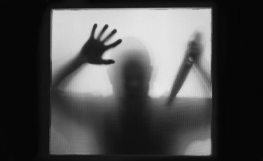 Korku, cadılar bayramı geçmişi, elinde bıçak tutan bir adamın camının arkasındaki gölgeli figür.