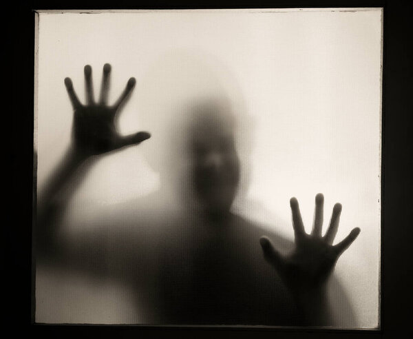 Horror, halloween background - Shadowy figure behind glass of a man