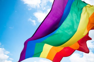 Parlak gökkuşağı Lgbt bayrağı mavi gökyüzüne karşı çırpınıyor. Aynı cinsiyetli çiftler için LGBT topluluğu, mutluluk, özgürlük ve aşk kavramı.
