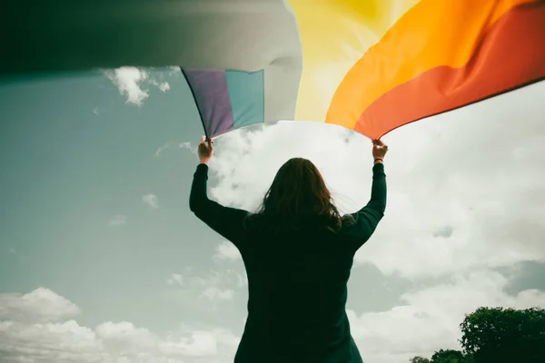 ゲイの虹の旗を持つ緑の草原に座っている女性 バイセクシャル レズビアン 性転換記号 同性カップルのための幸福 自由と愛の概念 — ストック写真