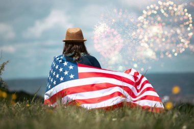 Amerikan bayrağı tutan ve havai fişeklerin keyfini çıkaran genç bir kadın. Bağımsızlık Günü kavramı. 