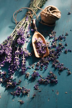 Turkuaz ahşap arka planda, tahta kepçe taze lavanta çiçeği. Aromaterapi, spa, masaj konsepti.
