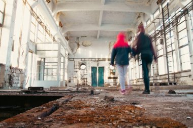 Anne ve kız mülteciler, savaş sırasında harap olmuş harabelerin üzerinde el ele tutuşarak umutla yürüyorlar.