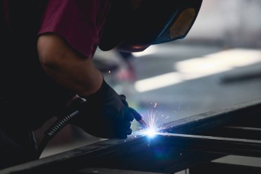 Handyman performing welding and grinding at his workplace in the workshop, while the sparks 