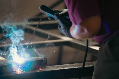 Etrafındaki kıvılcımlar uçuşurken tamirci atölyesinde kaynak ve öğütme yapıyordu. Koruyucu kask ve ekipman takıyor..